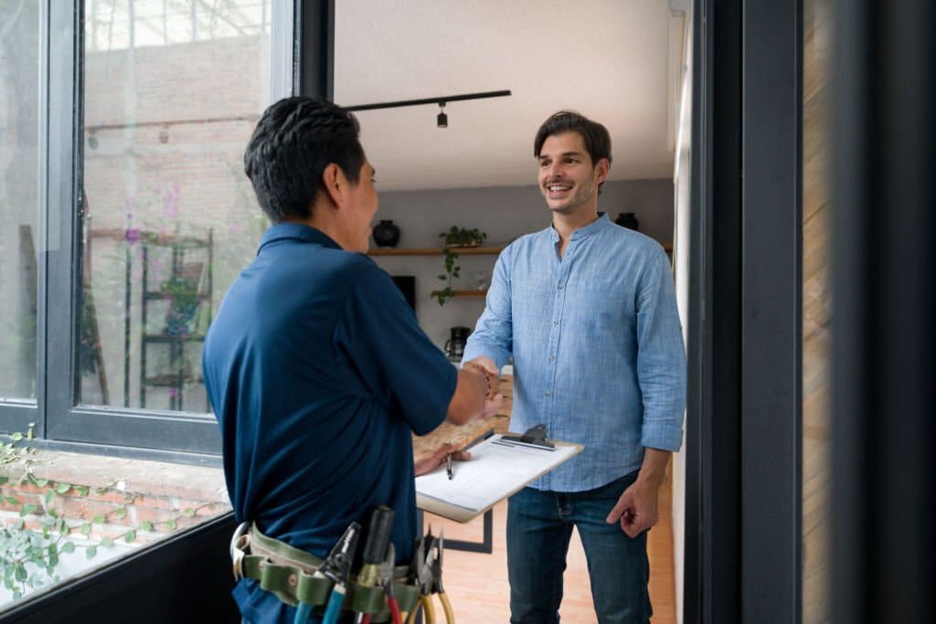 Un électricien salue un client avec une poignée de main à la porte de sa maison